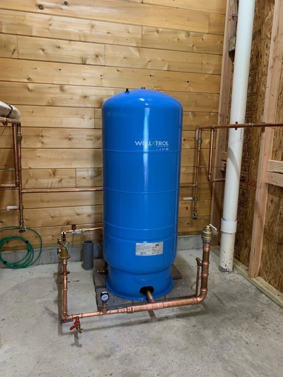 blue well pump in basement with copper pipes extending out
